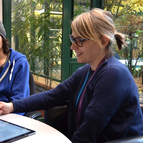 Librarian dressed in blue demonstrating work to a student in a meeting room