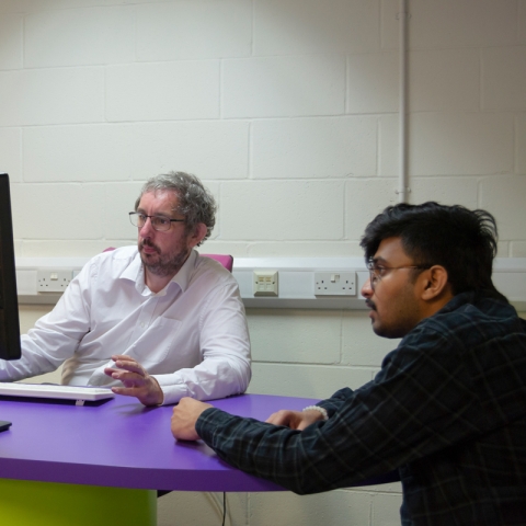 Librarian in white shirt advising a middle-eastern client at the Library Help Desk