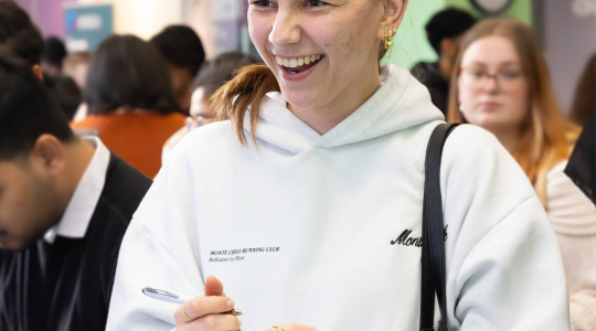 A female student talking to a member of staff in the Careers Centre while writing notes.