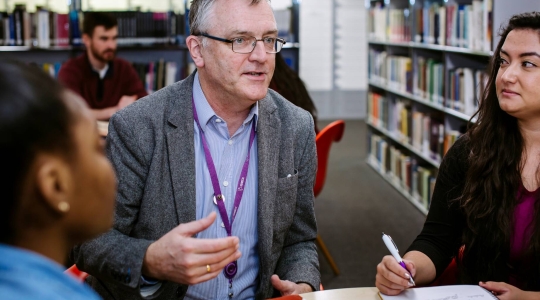Technology Faculty Librarian Timothy Collinson chatting with students in the Library