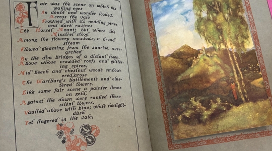 Photograph of a bound volume from the University Library Rare Books collection open at a page showing a poetical translation of a Wagnerian opera by TW Rolleston and an illustrative plate Willy Pogány.