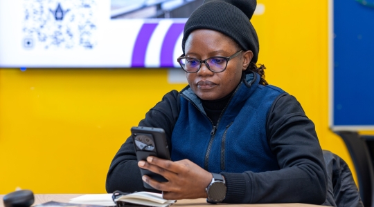 Black woman sat reading from her mobile phone