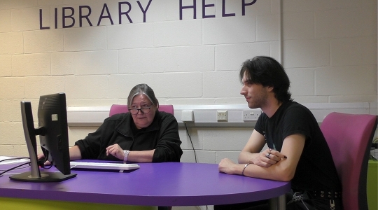 Librarian helping someone at the Library Help Desk