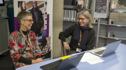 Two librarians sat at a referencing pop-up in the Library Atrium