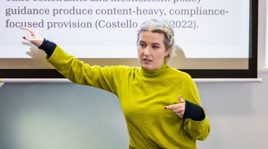 A student presenting in front of a slideshow.