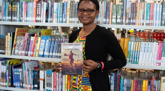 Alumnus and published author Florence Mukiria holding a copy of her debut novel