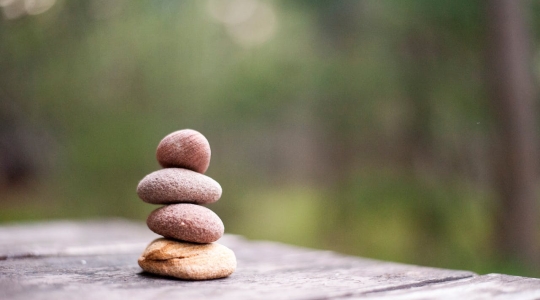 Stacked pebbles on a wooden table.   From Pexels - https://www.pexels.com/photo/four-rock-formation-668353/