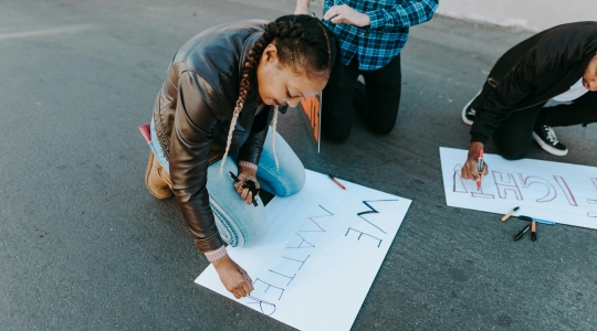Black woman crafting a protest sign reading "We matter" (in support of the Black Lives Matter campaign)