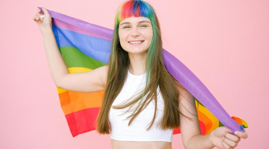 Woman with hair dyed into rainbow stripes holding a rainbow flag - Pexels, https://www.pexels.com/photo/woman-holding-a-gay-pride-flag-4611969/