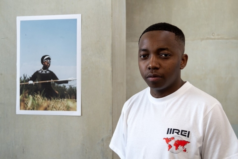 Visual artist Coltart Sithole standing beside one of his photographs displayed in the University Library