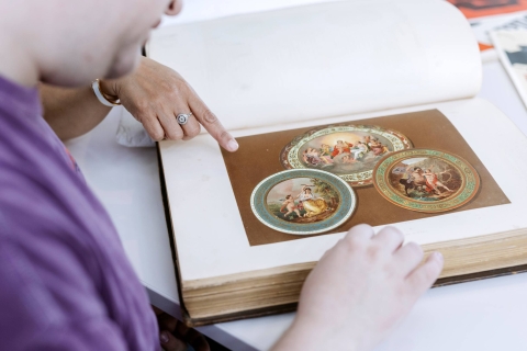 Students poring over a print of a classical artwork design in a book