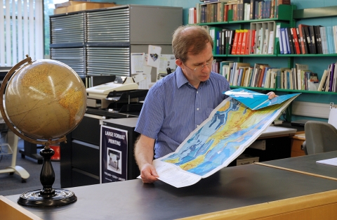 David Sherren, Map Librarian, studying a map in the University Map Library 