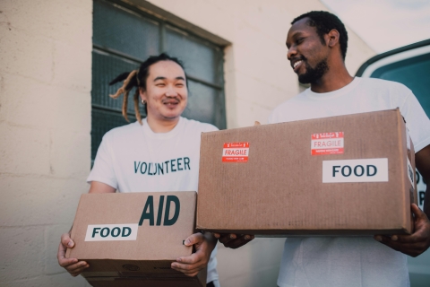 Two volunteers carrying boxes of food aid