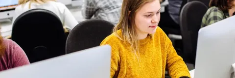 Students in computer suite in yellow jumper