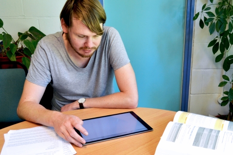 Young man chatting with staff using a tablet computer