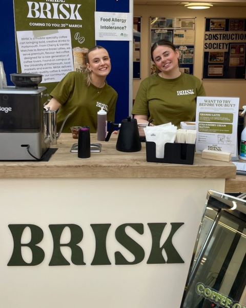 Isobel and Lizzie - the brains and baristas behind student enterprise Brisk Coffee posing in their mobile coffee cart