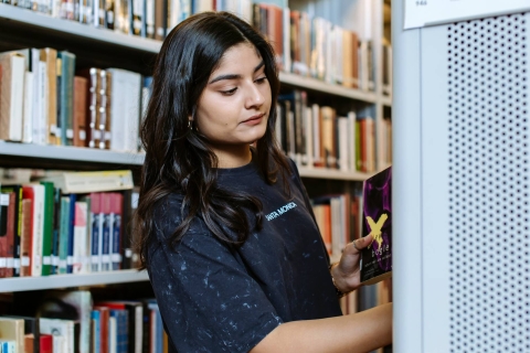 Asian woman browsing bookshelves in the Library