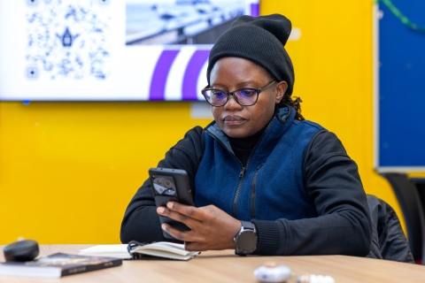 Black woman sat reading from her mobile phone