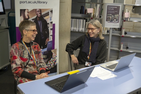Two librarians sat at a referencing pop-up in the Library Atrium