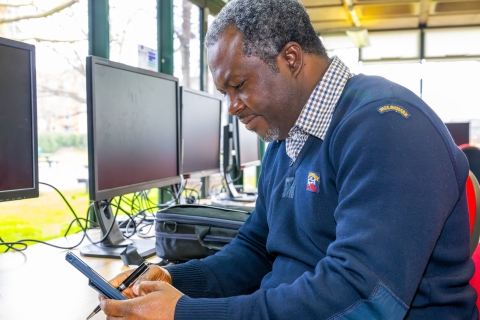 Mature Black man sat in the Library Postgraduate Study Suite using a mobile phone