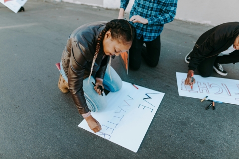 Black woman crafting a protest sign reading "We matter" (in support of the Black Lives Matter campaign)
