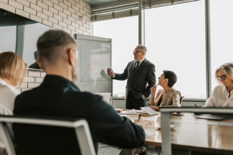 A meeting chaired by a middle aged white man, representing a think tank - from Pexels, https://www.pexels.com/photo/business-partners-having-a-meeting-at-the-office-7433898/