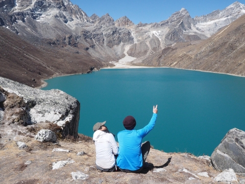 Man and woman sat looking at a sunrise over a peaceful mountain lake - from Pixabay, https://pixabay.com/images/search/person%20looking%20at%20sunrise/