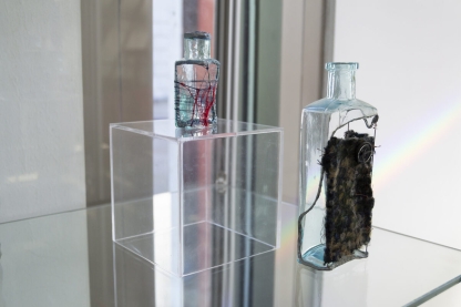 Broken, backless bottles with cloth stitched across the gaps