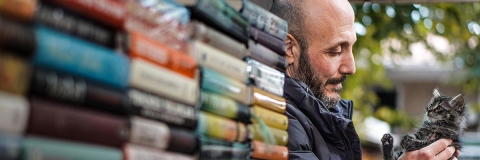 Man holding a cat outside a bookshop in Istanbul