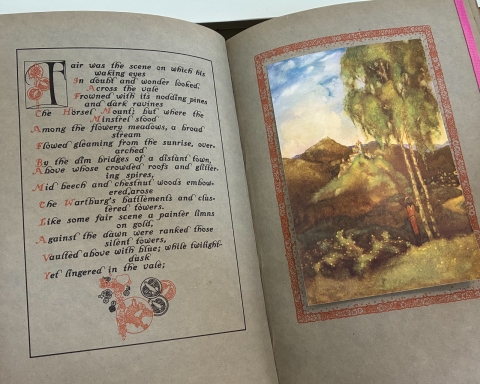 Photograph of a bound volume from the University Library Rare Books collection open at a page showing a poetical translation of a Wagnerian opera by TW Rolleston and an illustrative plate Willy Pogány.
