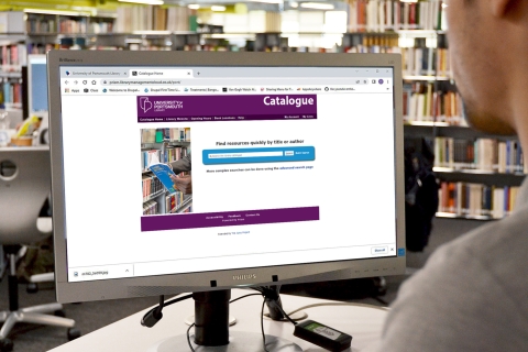 A student looking at the library catalogue on a computer screen