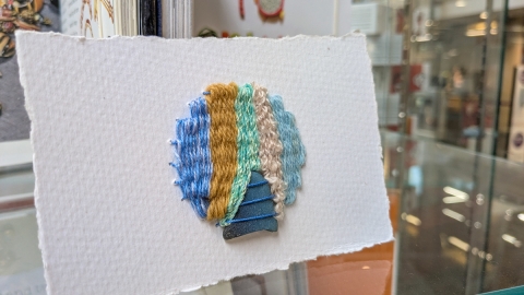 Woven broach incorporating a piece of blue sea glass