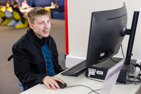 Student using a wheelchair studying at one of the Library's accessible (adjustable height) computer workstations