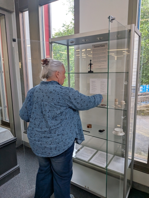 Amanda Garrie placing antique heirlooms from her grandmother into the display cabinet at the exhibition