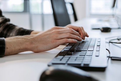 Close-up of hands typing on a laptop keyboard.