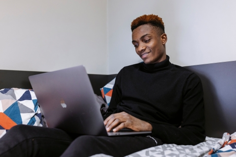 A student using a laptop while sitting on a sofa.